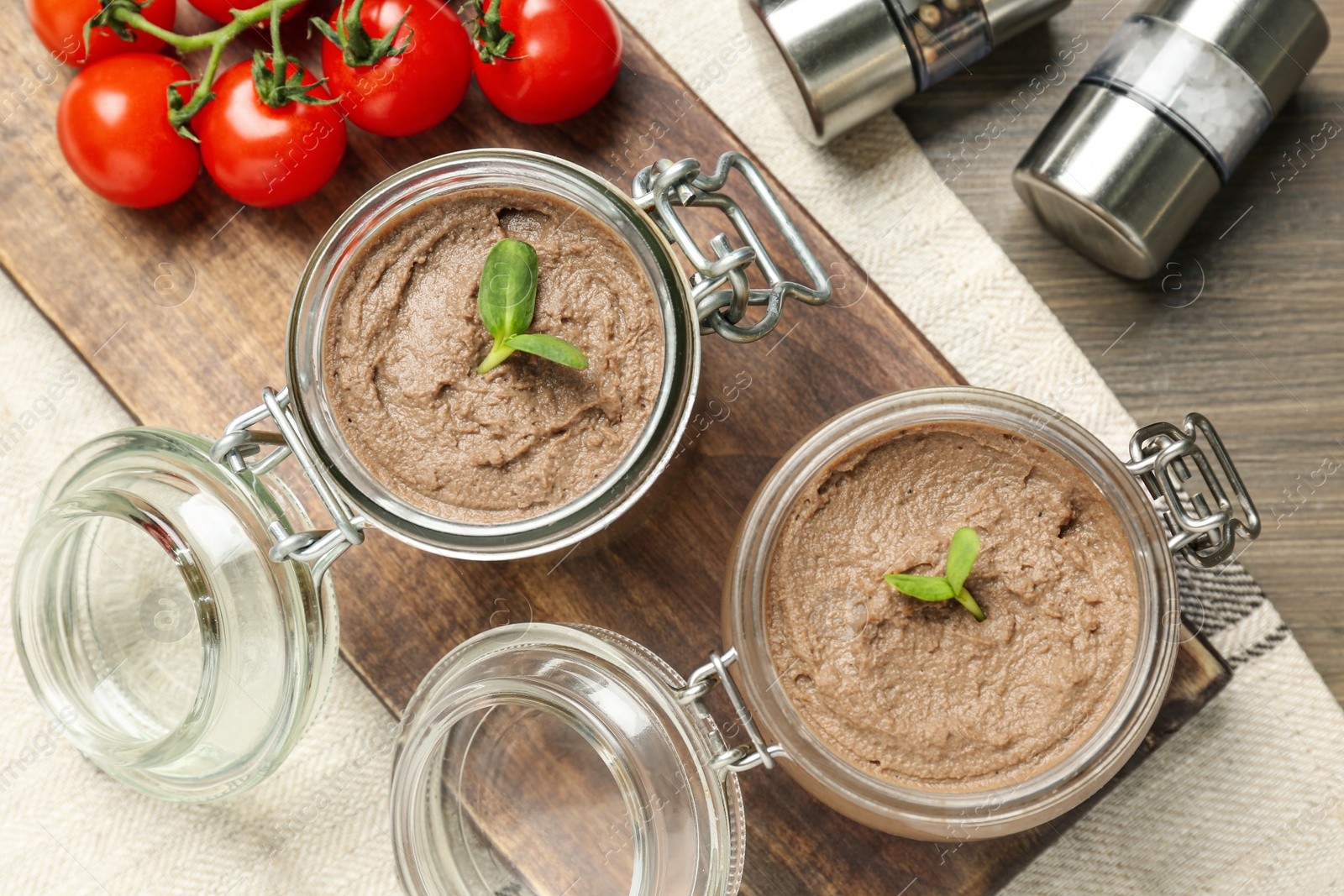 Photo of Glass jars with delicious liver pate on wooden table, flat lay