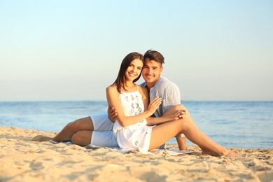 Photo of Happy young couple sitting together on beach