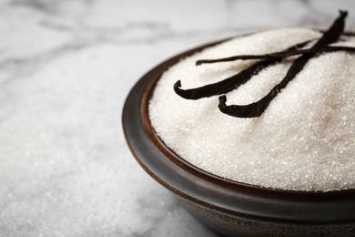 Photo of Bowl of aromatic vanilla sugar and sticks on light background