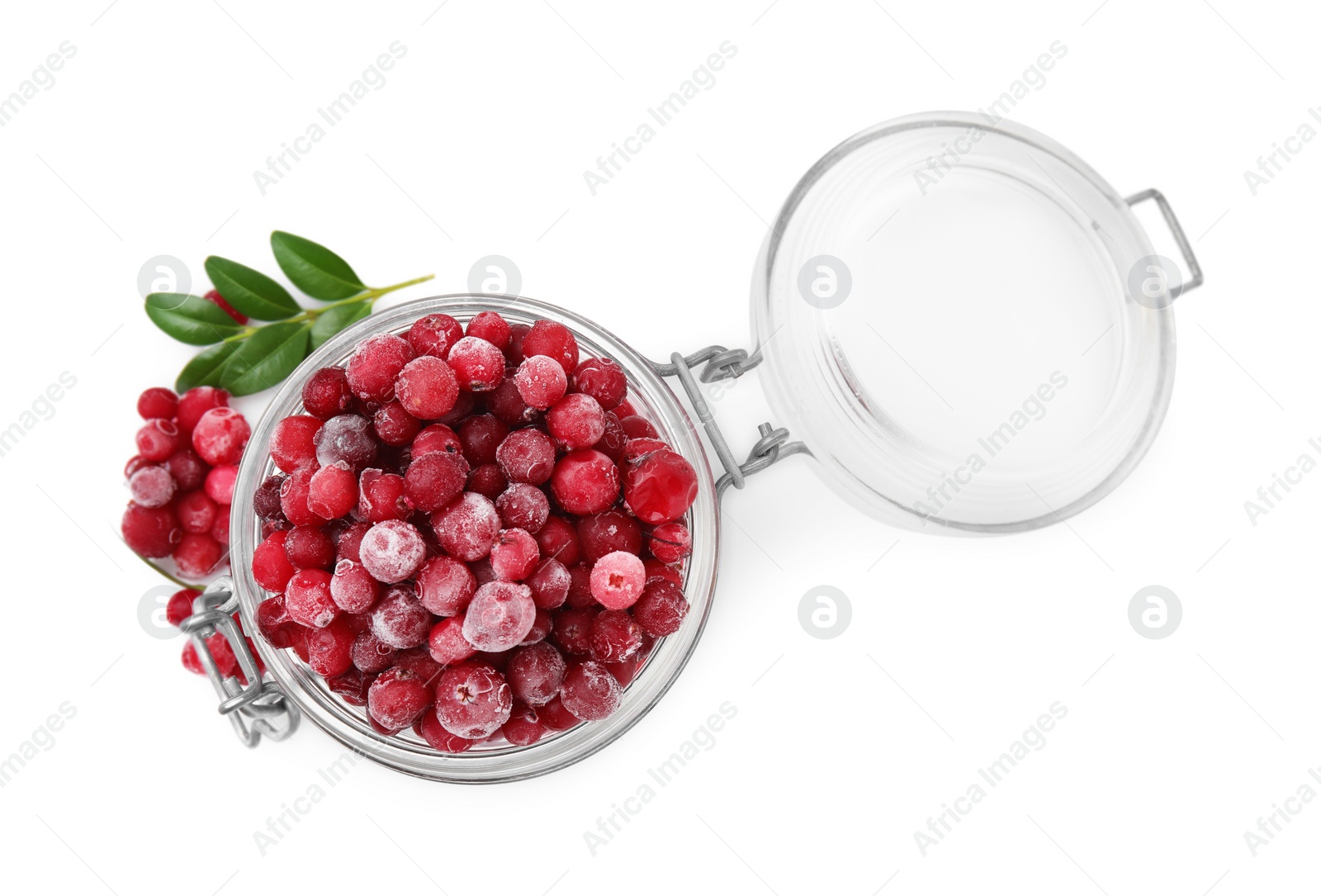 Photo of Frozen red cranberries in glass jar and green leaves isolated on white, top view