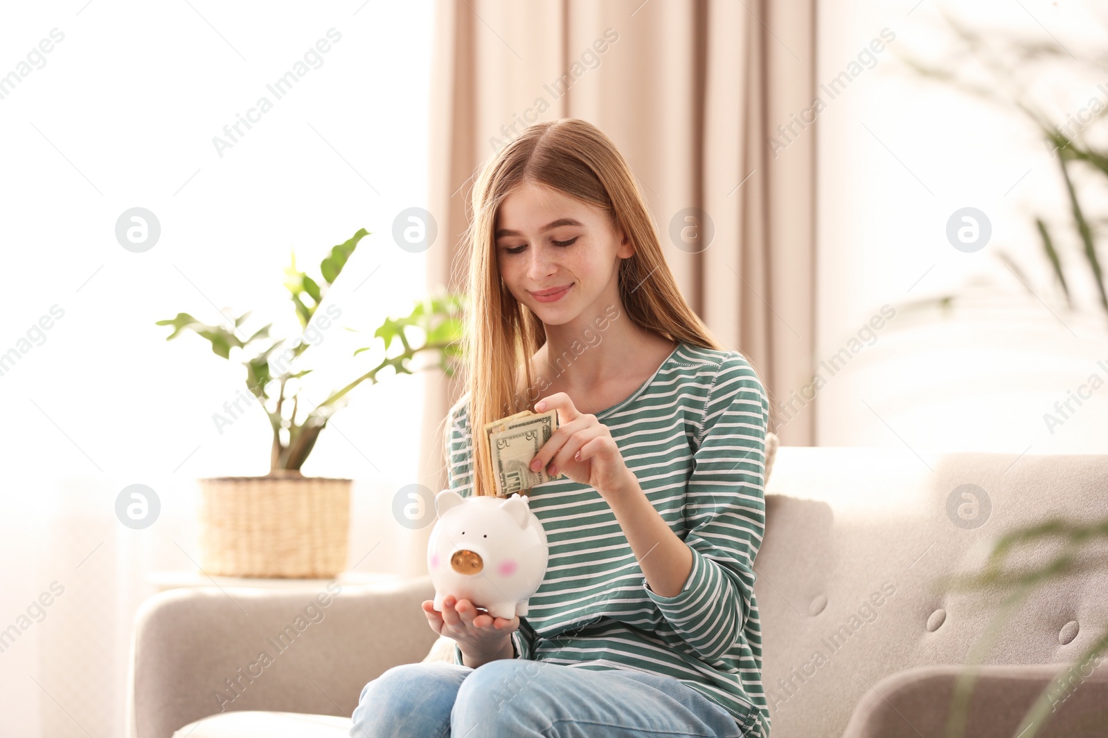 Photo of Teen girl with piggy bank and money at home