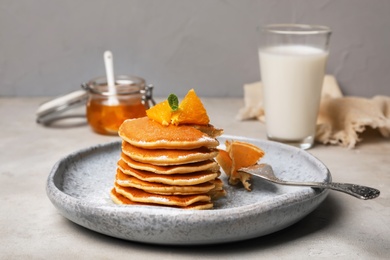 Tasty pancakes with orange on table