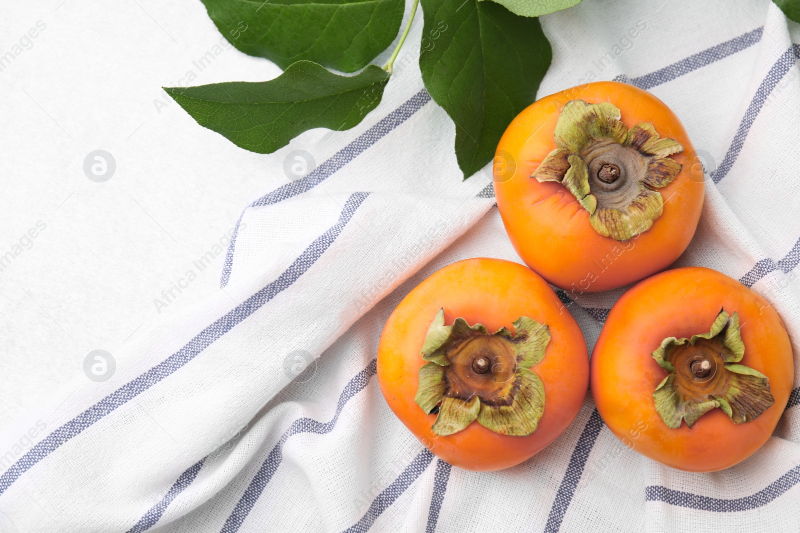 Photo of Delicious ripe juicy persimmons on light table, flar lay