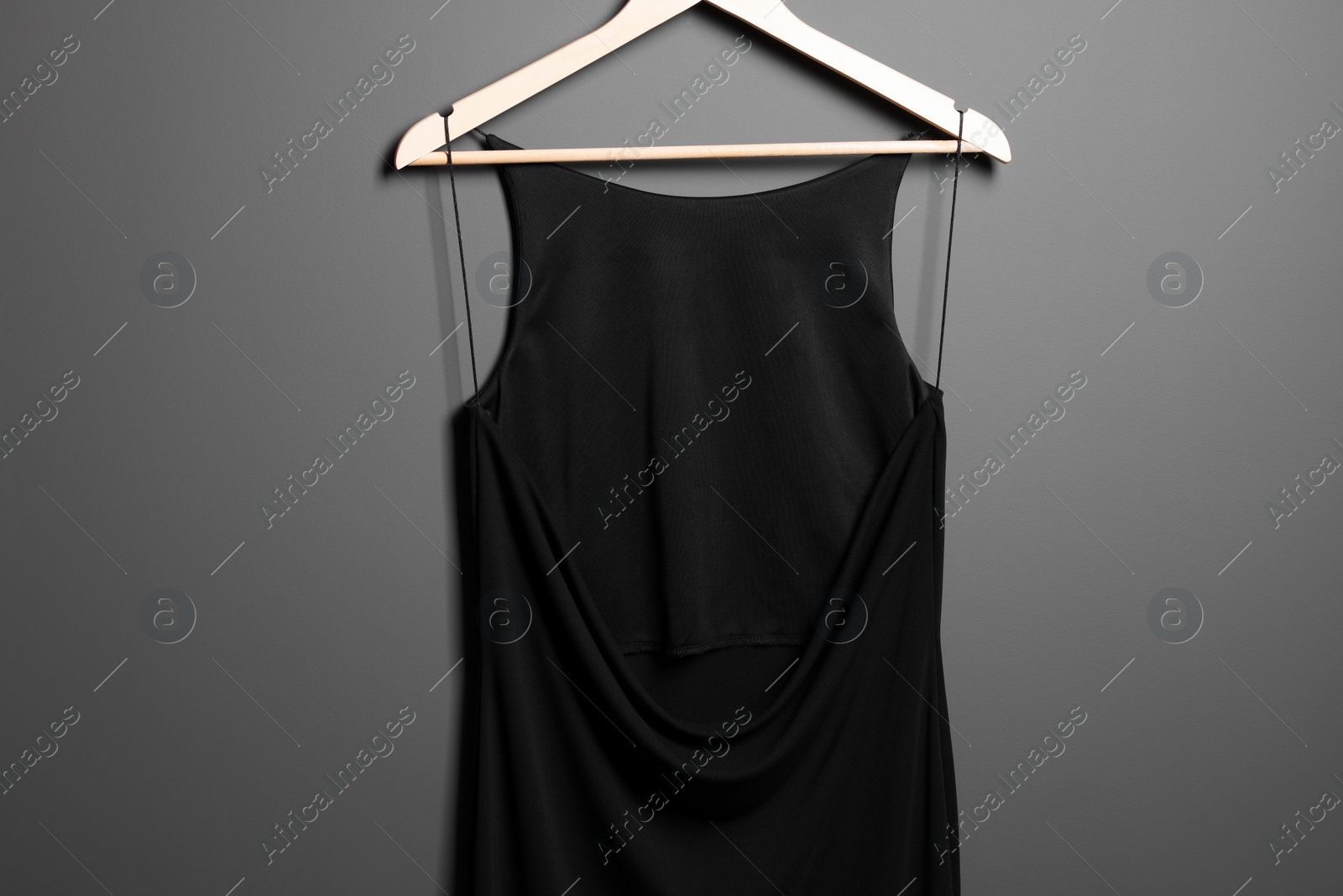 Photo of Beautiful black women's party dress on hanger near grey wall. Stylish trendy clothes for high school prom