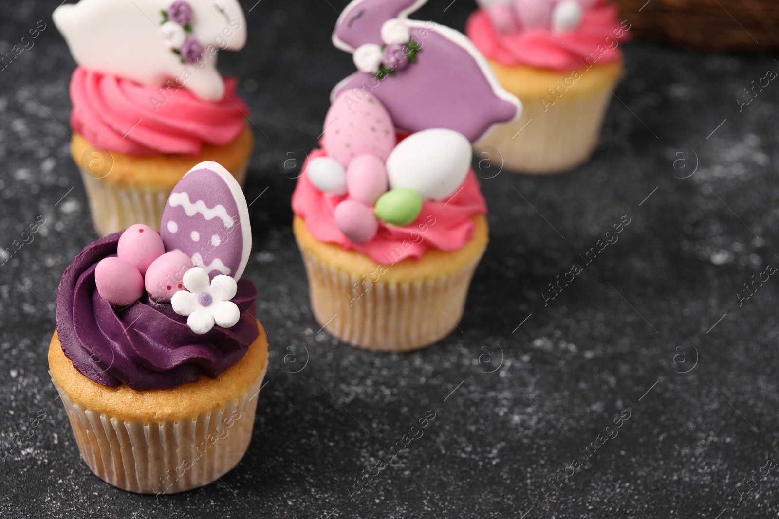 Photo of Tasty decorated Easter cupcakes on grey table, space for text