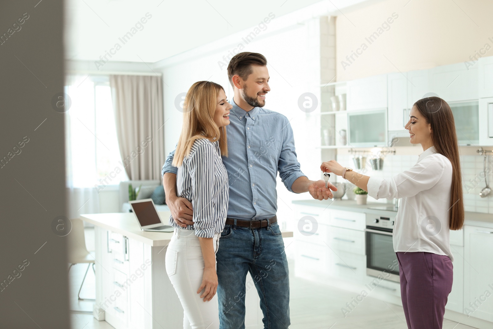 Photo of Female real estate agent giving house key to couple indoors