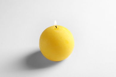 Round wax candle burning on white background