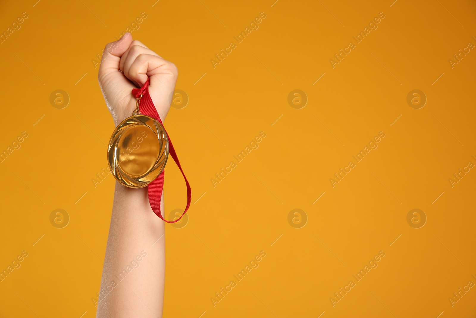 Photo of Woman holding gold medal on yellow background, closeup. Space for text