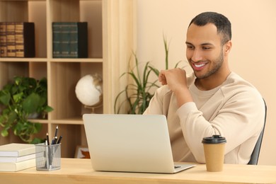 Photo of Smiling African American man with laptop at table in room