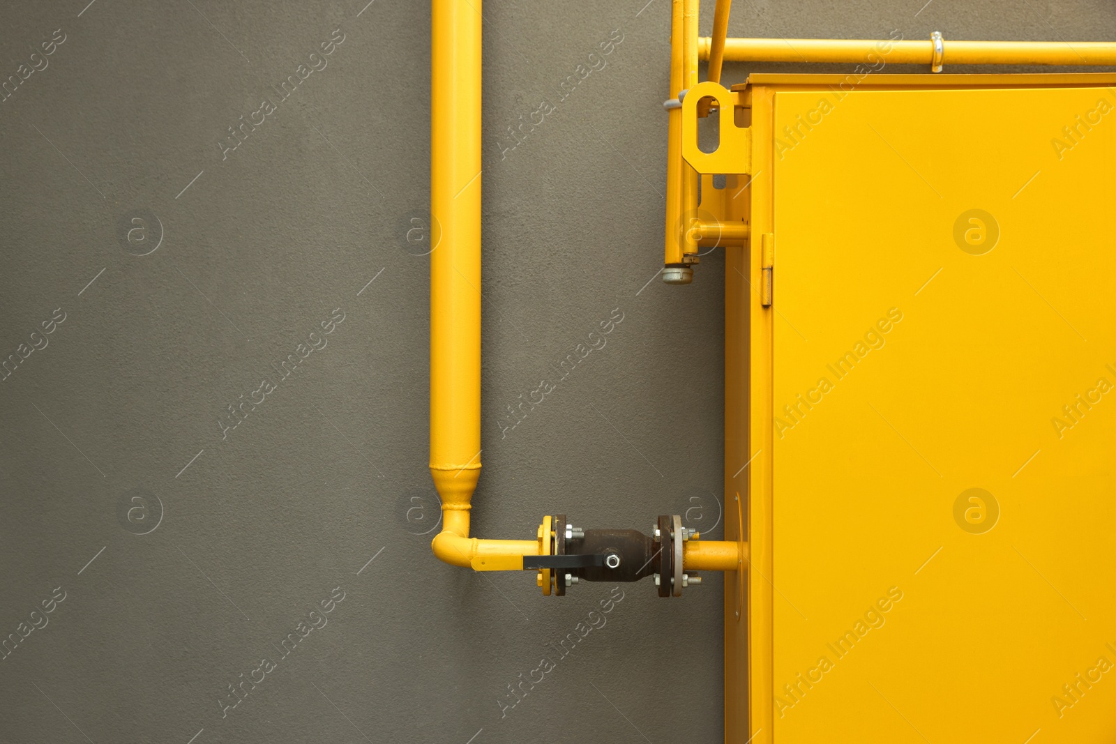 Photo of Yellow gas distribution cabinet near brown wall outdoors