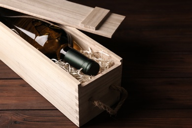 Photo of Open wooden crate with bottle of wine on table