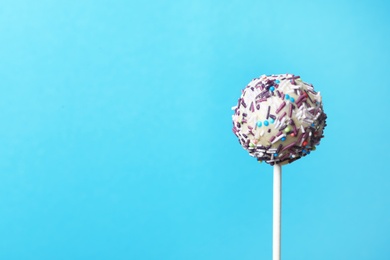 Photo of Yummy bright cake pop on color background. Space for text