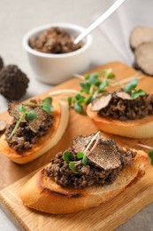 Tasty bruschettas with truffle paste on wooden board, closeup