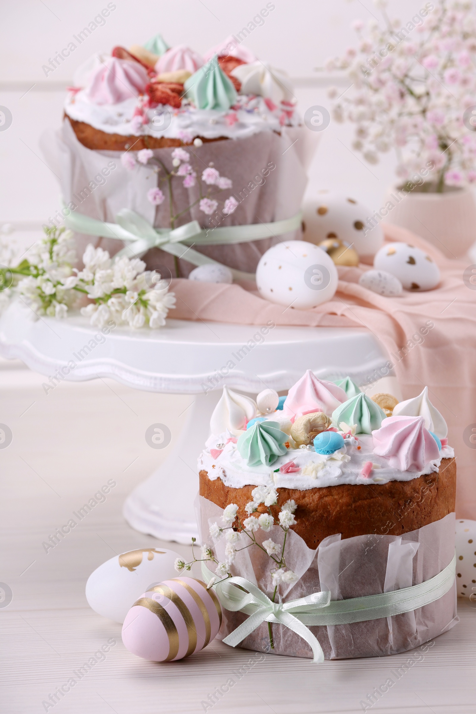 Photo of Traditional Easter cakes with meringues and painted eggs on white wooden table