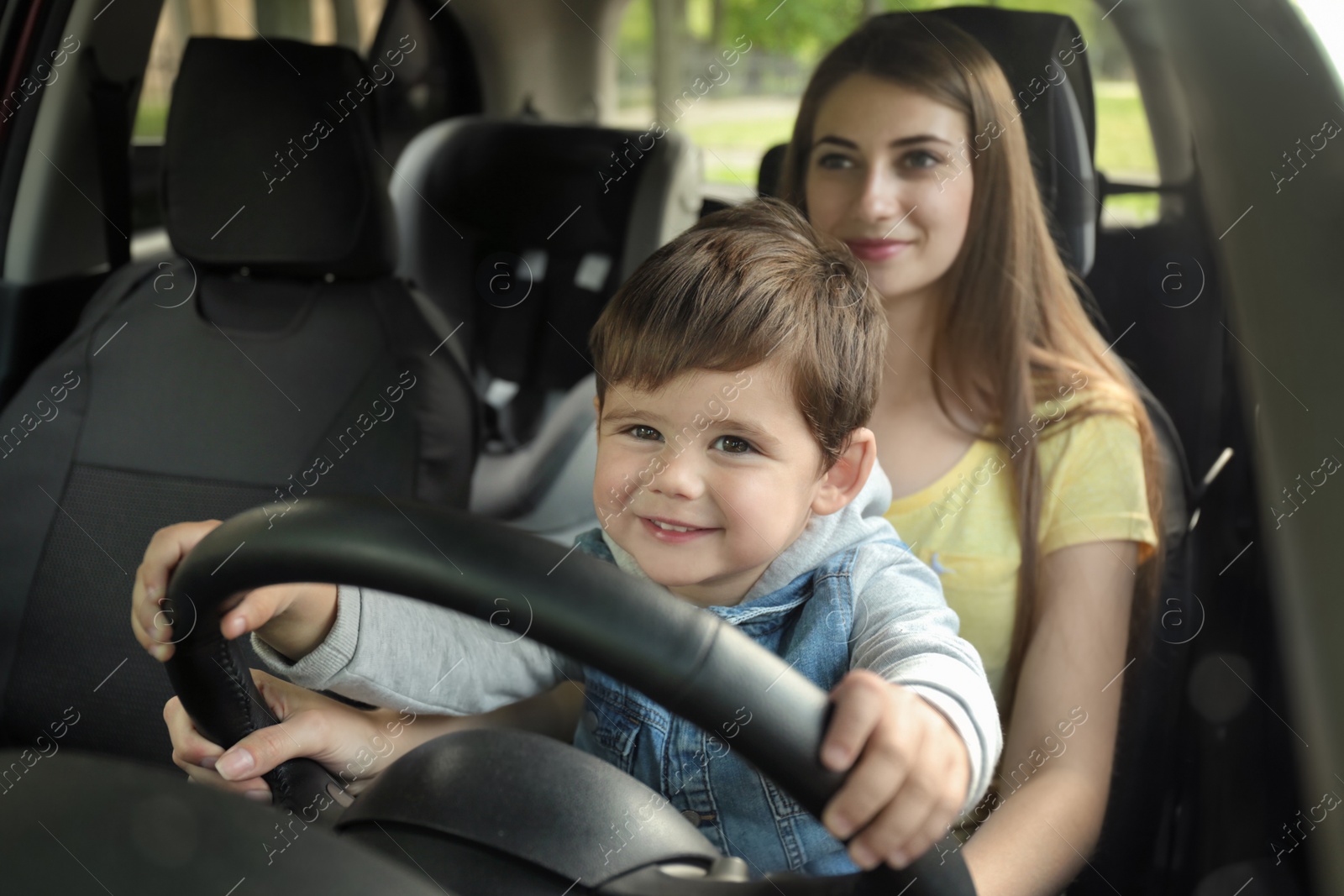 Photo of Mother with little son driving car together. Child in danger