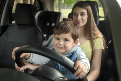 Mother with little son driving car together. Child in danger