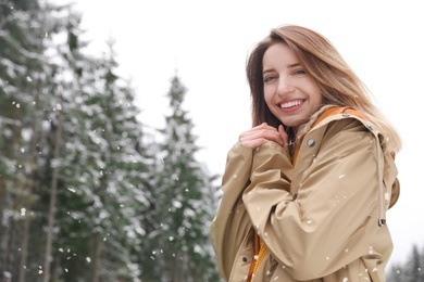 Young woman in warm clothes outdoors on snowy day, space for text. Winter vacation