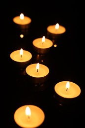 Burning candles on mirror surface in darkness