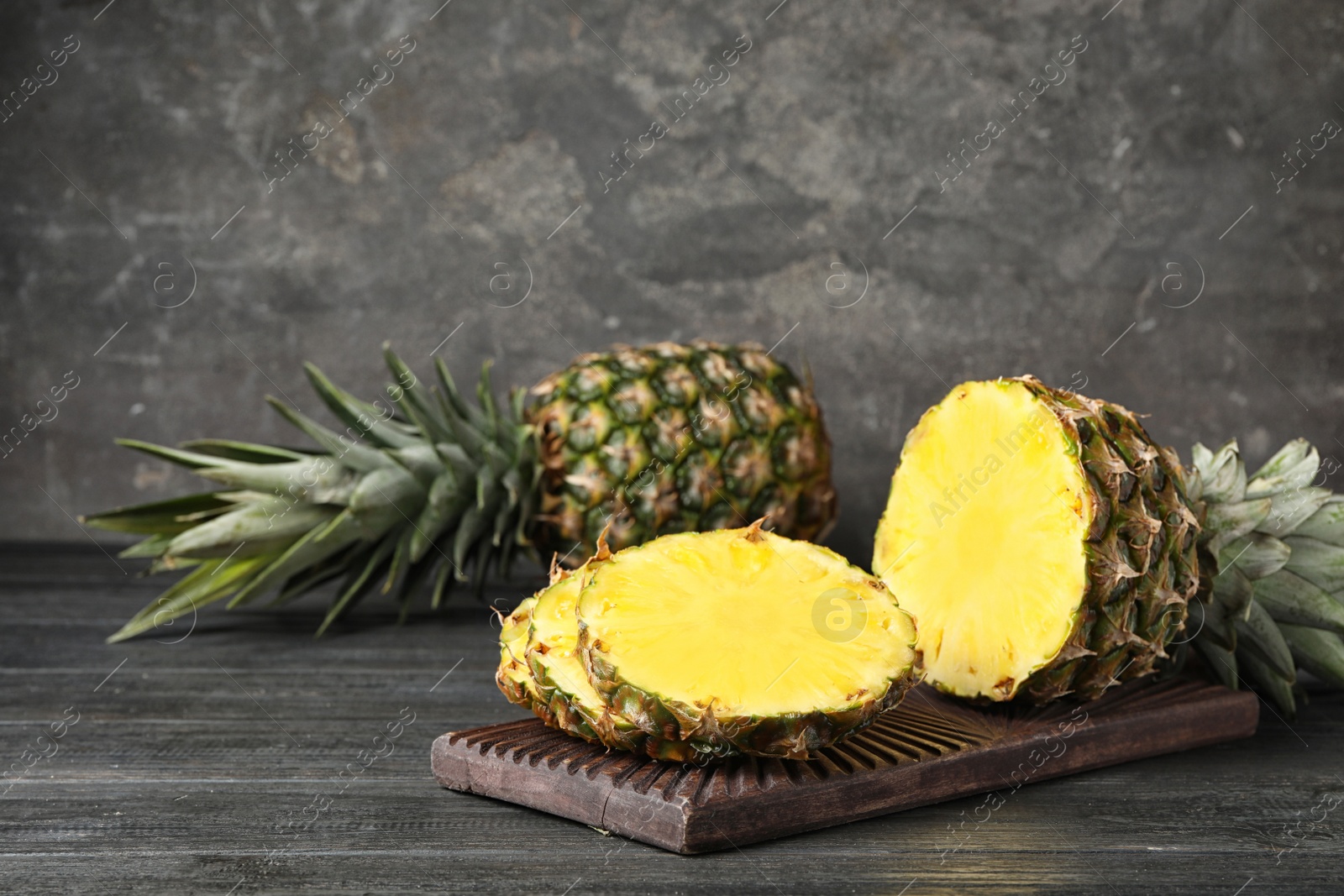 Photo of Board with cut fresh juicy pineapple on wooden table, space for text