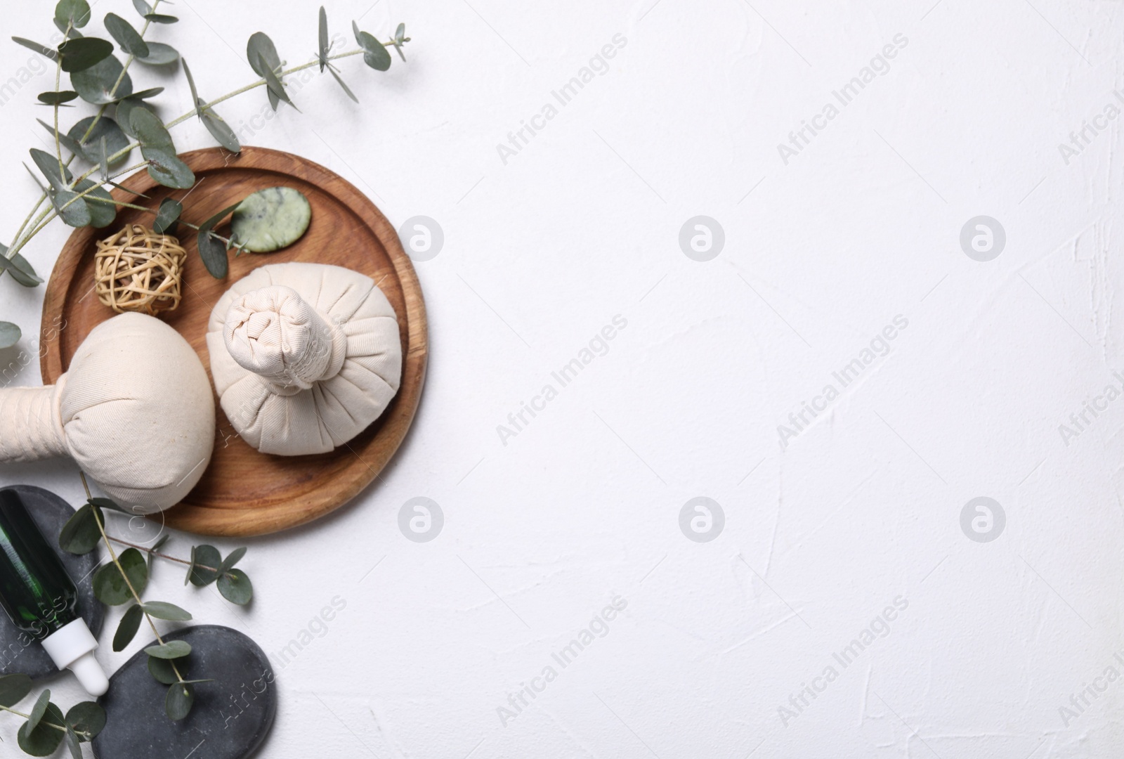 Photo of Flat lay composition with herbal massage bags, spa products and eucalyptus branches on white table. Space for text