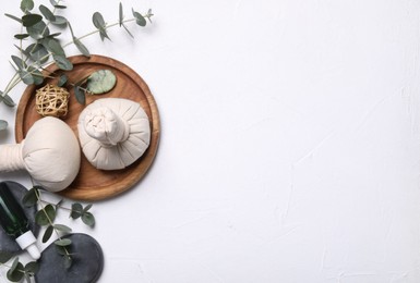 Flat lay composition with herbal massage bags, spa products and eucalyptus branches on white table. Space for text