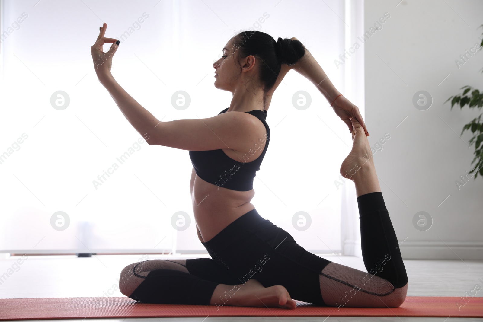 Photo of Woman practicing one legged king pigeon asana in yoga studio. Eka pada rajakapotasana pose