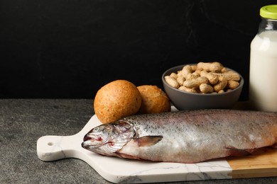 Photo of Allergenic food. Different fresh products on gray table against dark background, closeup with space for text