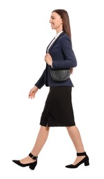 Young businesswoman with stylish bag walking on white background