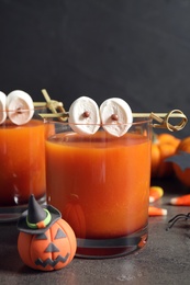 Decorated glasses with drinks on grey table, closeup. Halloween celebration