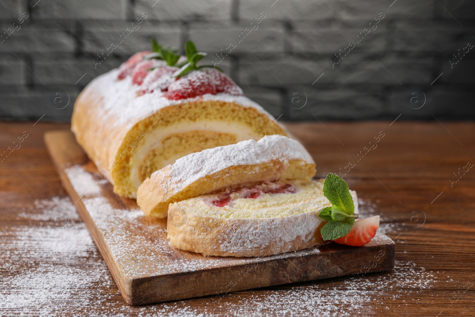 Photo of Pieces of delicious cake roll with strawberries and cream on wooden table