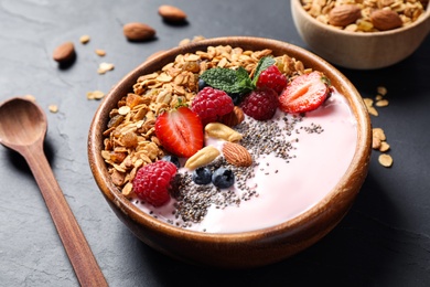 Photo of Tasty homemade granola with yogurt on dark grey table, closeup. Healthy breakfast