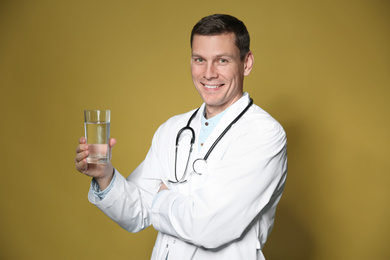 Nutritionist holding glass of pure water on yellow background