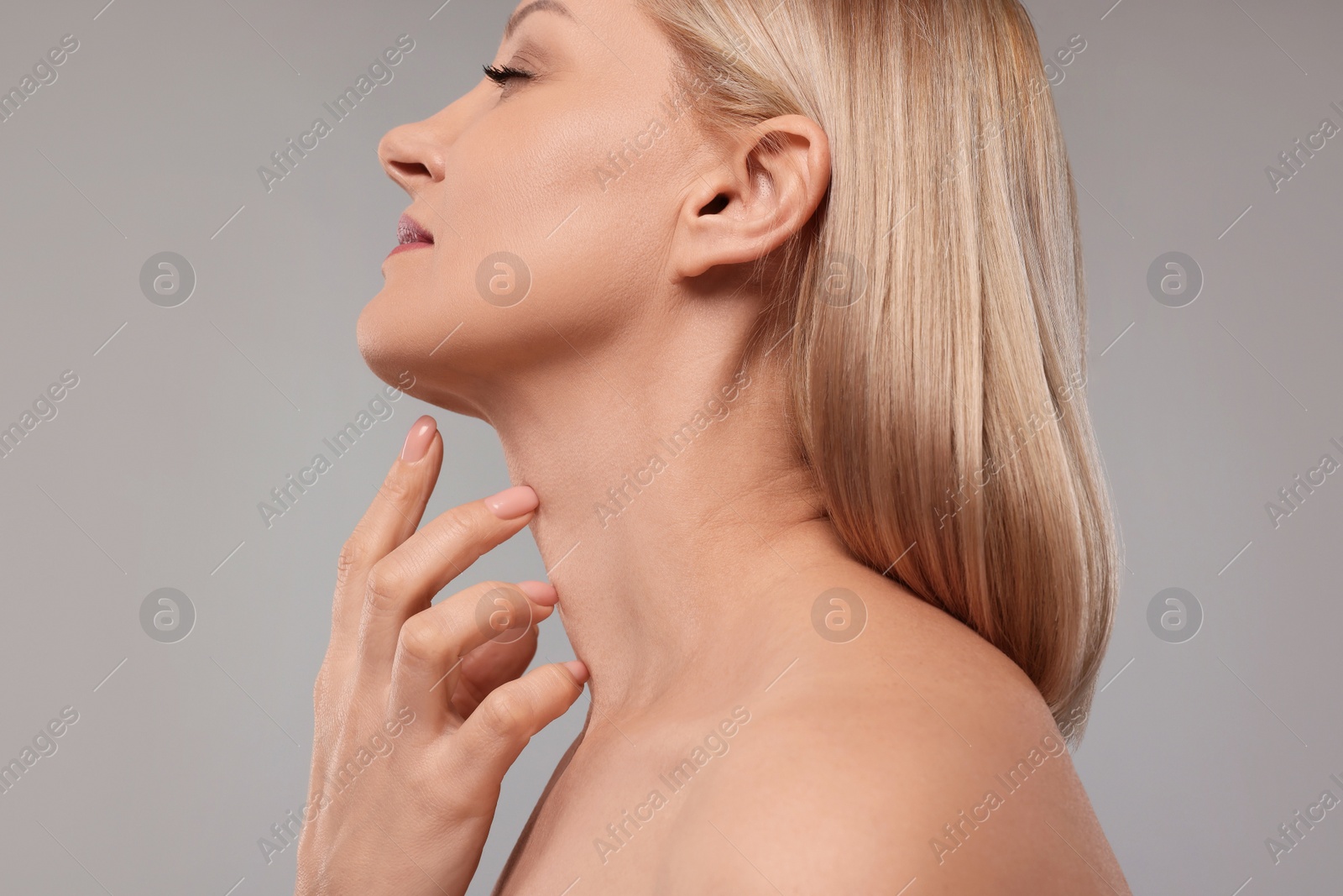 Photo of Beautiful woman touching her neck on grey background