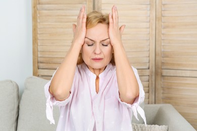 Photo of Woman suffering from headache on sofa at home. Hormonal disorders
