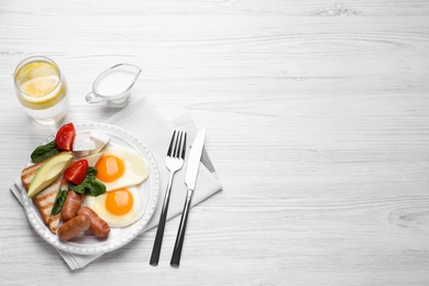 Delicious breakfast with fried eggs served on white wooden table, flat lay. Space for text