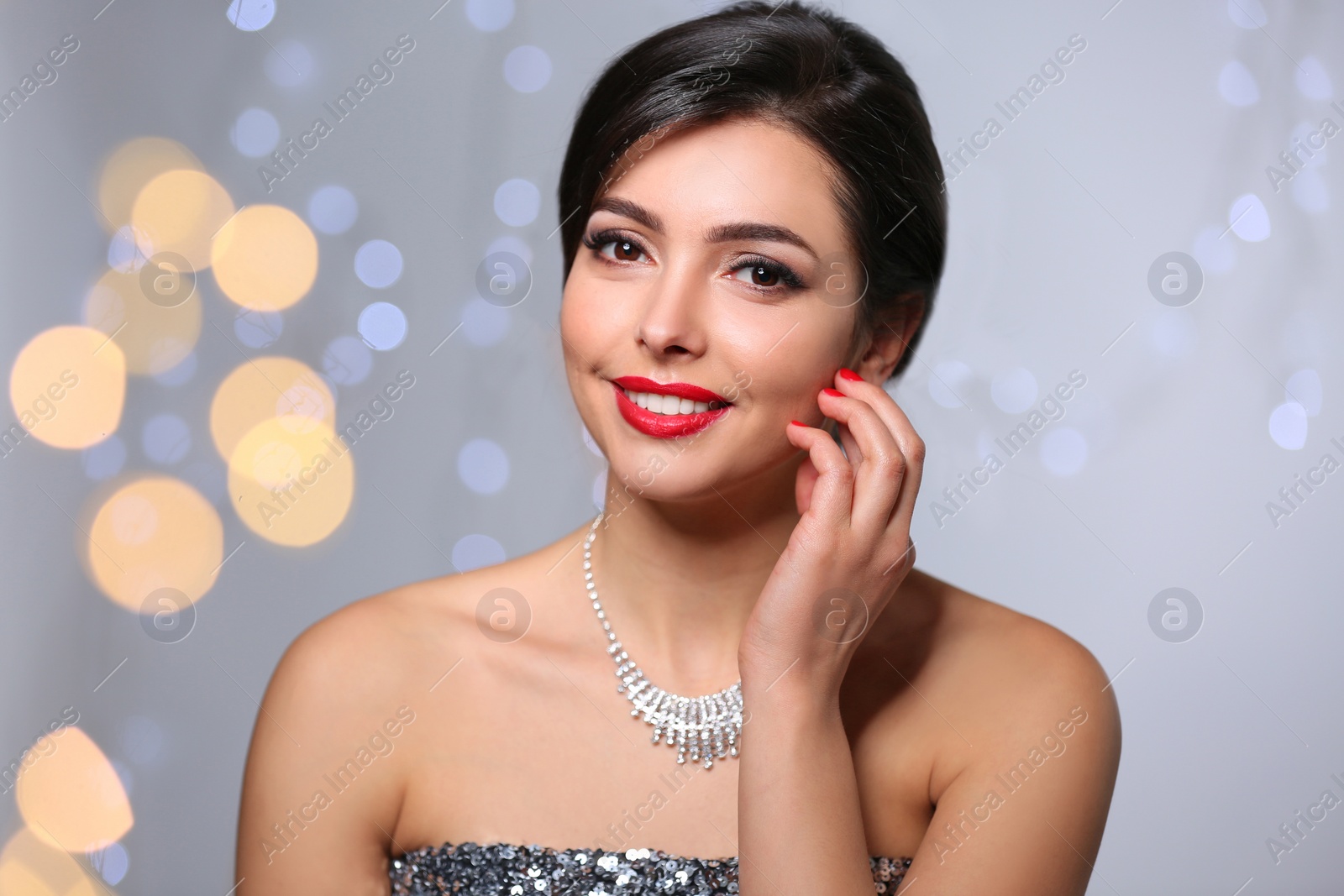 Photo of Beautiful woman with elegant jewelry on blurred background