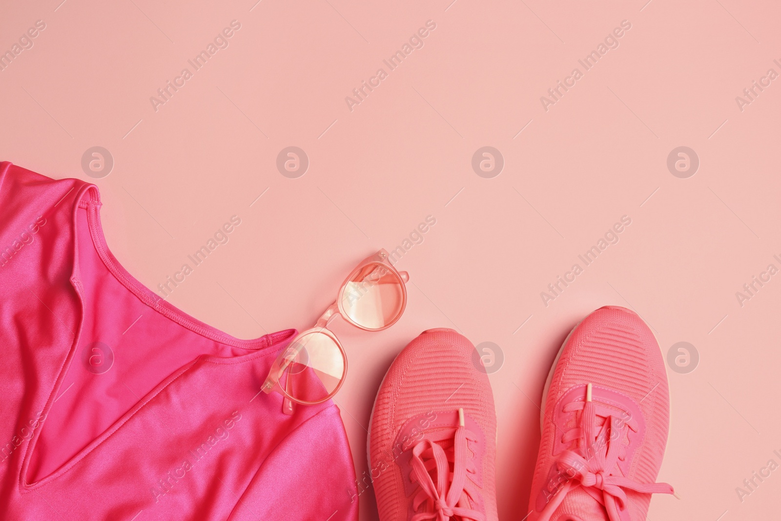 Photo of Stylish sunglasses, pink sneakers and t-shirt on color background, flat lay. Space for text