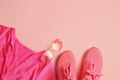 Photo of Stylish sunglasses, pink sneakers and t-shirt on color background, flat lay. Space for text