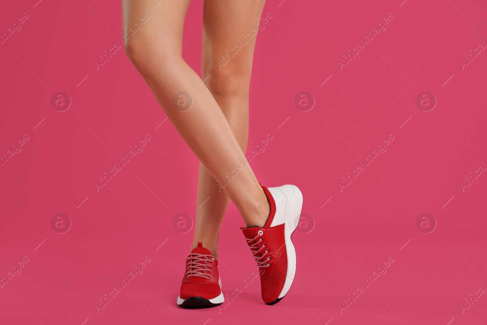 Photo of Woman wearing sneakers on pink background, closeup