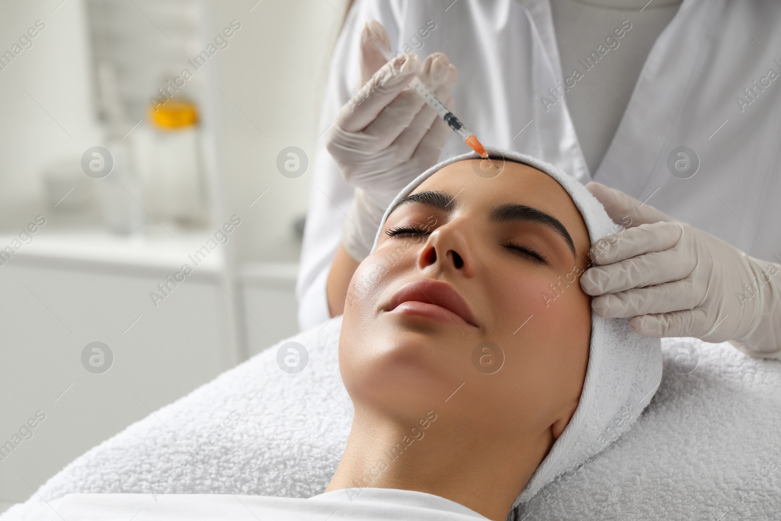 Photo of Doctor giving facial injection to young woman in clinic, space for text. Cosmetic surgery