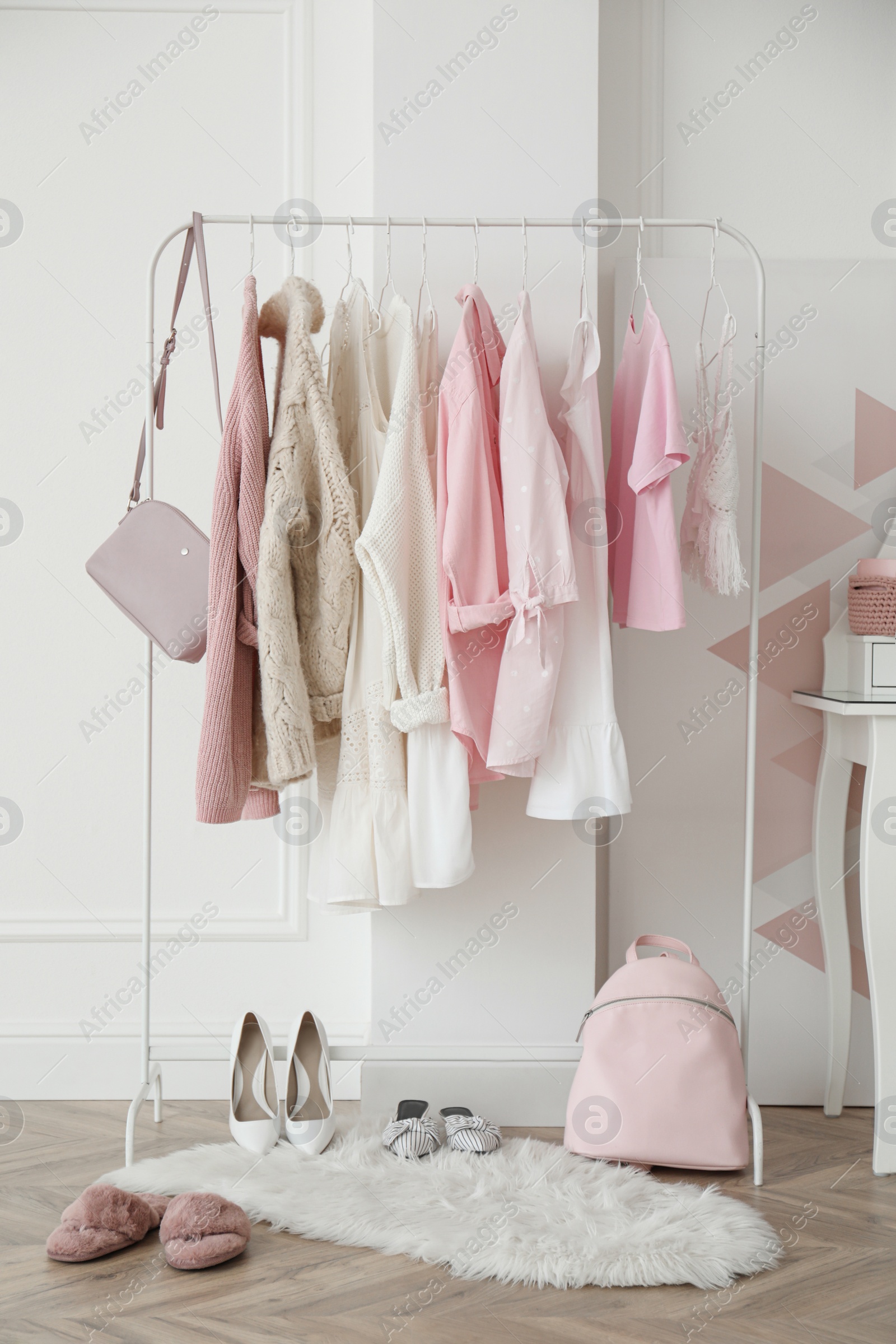 Photo of Rack with stylish clothes near white wall in dressing room