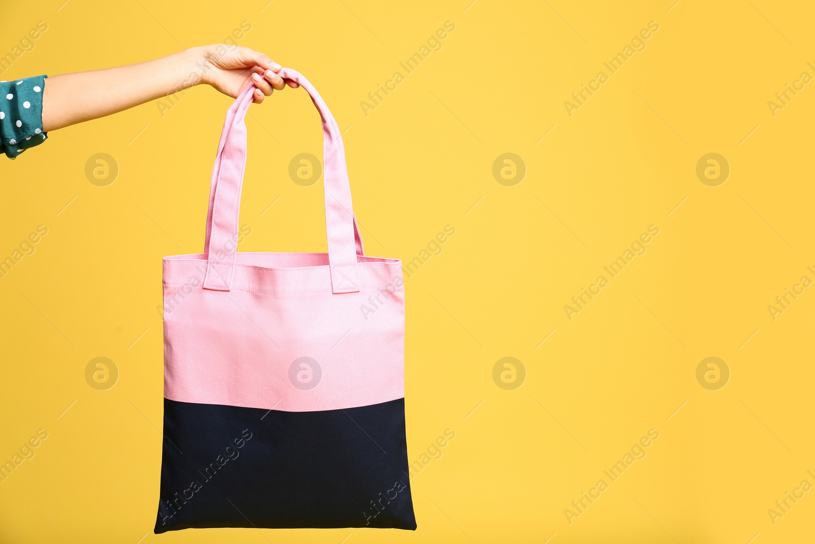 Photo of Young woman holding textile bag on yellow background, closeup. Space for text