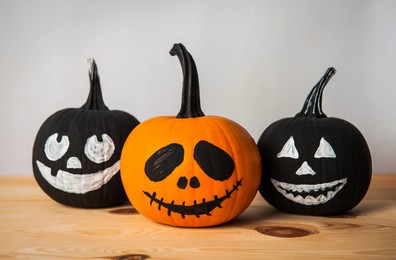 Photo of Halloween celebration. Pumpkins with spooky drawn faces on wooden table