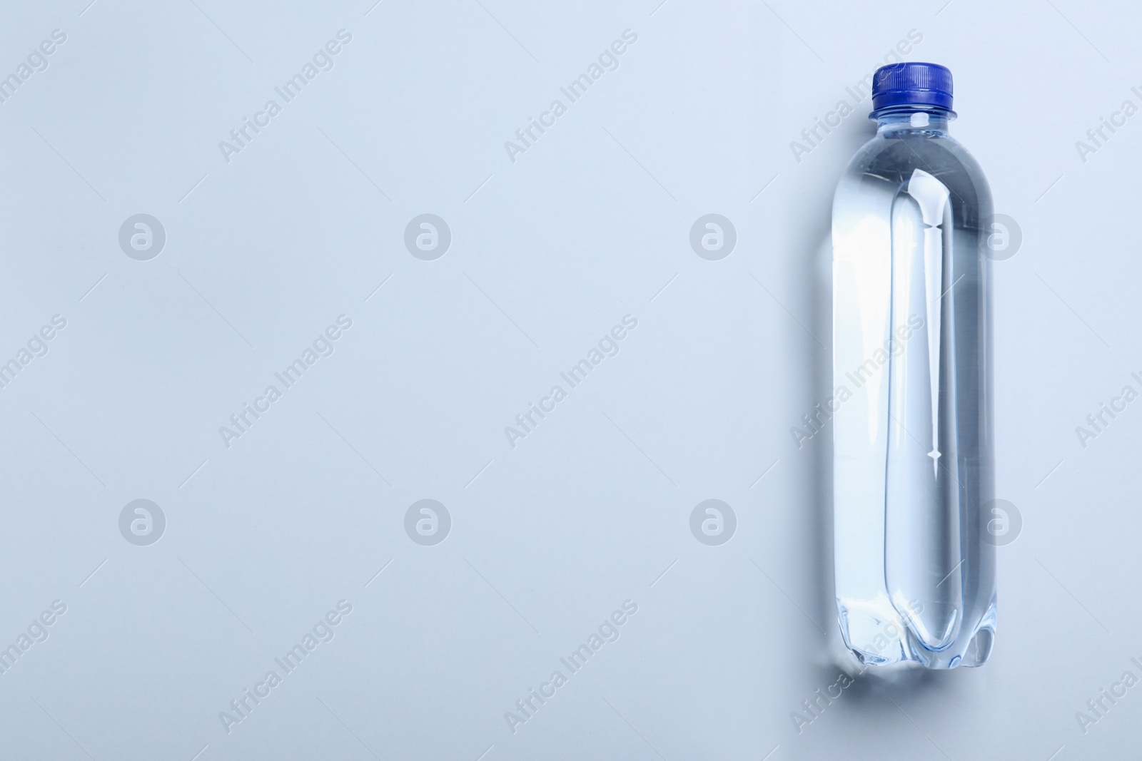Photo of Plastic bottle with water on white background, top view. Space for text