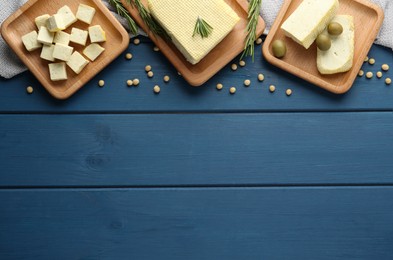 Photo of Cut tofu, olives and soya beans on blue wooden table, flat lay. Space for text