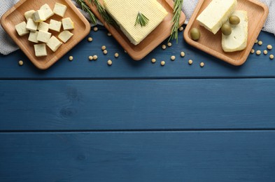 Cut tofu, olives and soya beans on blue wooden table, flat lay. Space for text