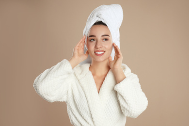 Photo of Beautiful young woman in bathrobe on brown background