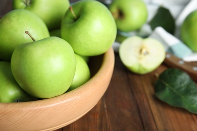 Fresh ripe green apples in bowl on wooden table, closeup. Space for text