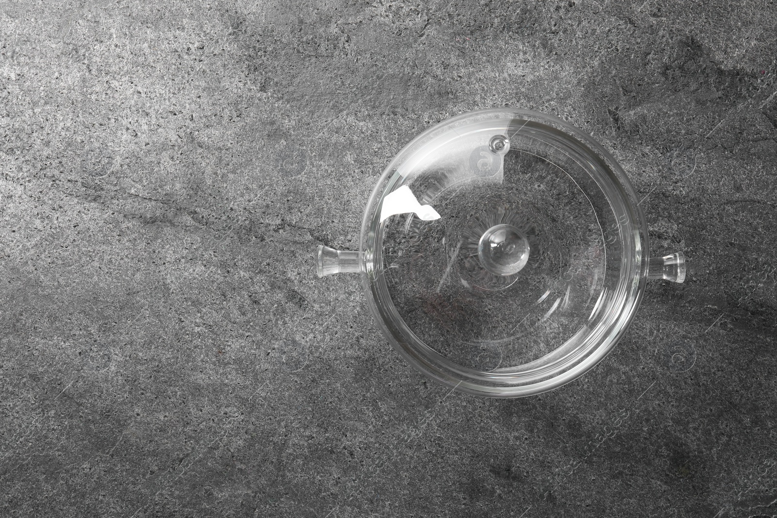 Photo of Glass pot with lid on grey table, top view. Space for text