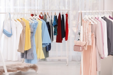 Photo of Racks with stylish clothes in light room